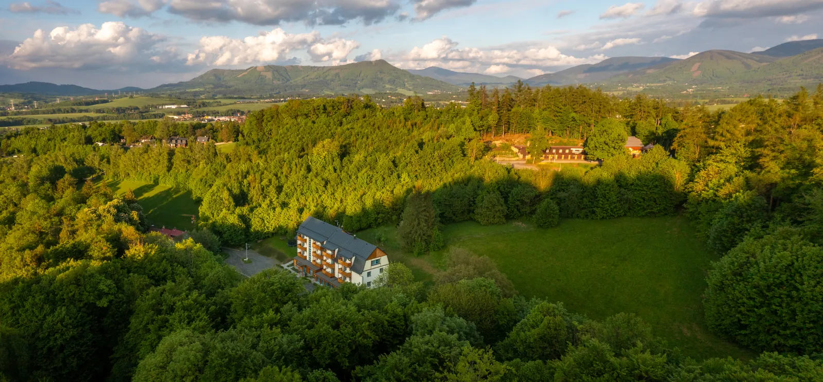 Panorama Beskyd z výšky, v popředí Hotel Edvard mezi lesy a loukami